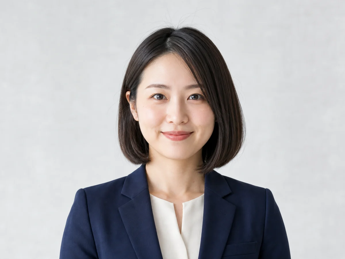 転職プロフィールの一枚 — 明るいグレー背景と控えめなジャケットで、顔と表情が伝わる構図に整えます。