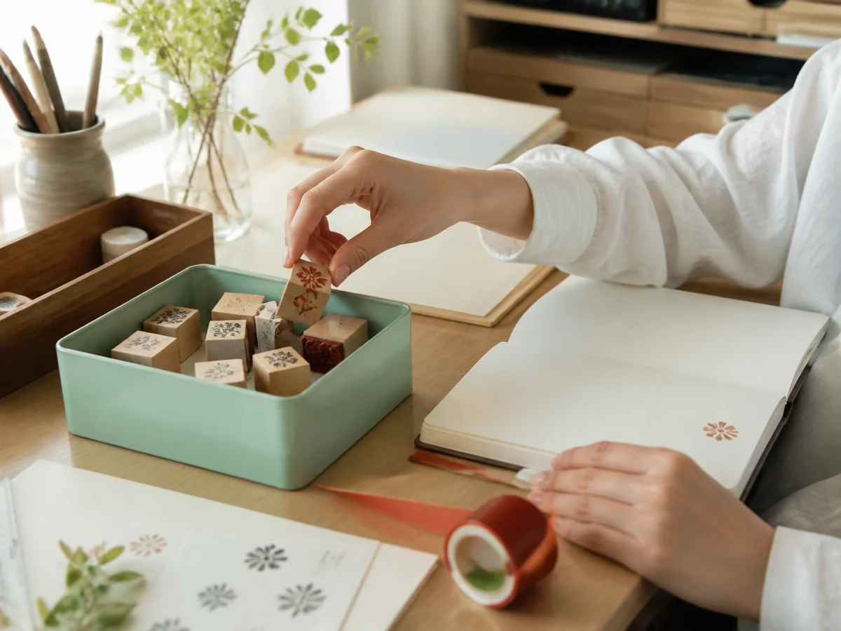 複数の参照を自然な商品シーンにまとめる — トレー、ノート、テープ、スタンプにそれぞれ役割を持たせ、寸法、接地、手元、木・紙・金属の質感が自然につながるか確認します。